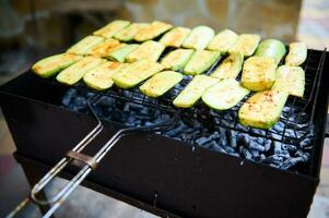 Close-up of zucchini slices, being marinated and cooked over flaming charcoal barbecue grill in the backyard. BBQ party photo