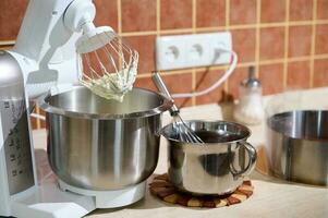 Focus on electric modern food processor with planetary mixer with whipped egg whites or whipped cream on kitchen counter photo