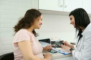 Doctor gynecologist obstetrician consulting a pregnant patient about the ultrasound scan of baby in gynecological clinic photo