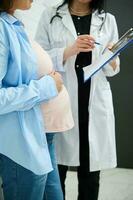 Mid-section image. Unrecognizable female doctor explaining ultrasound scan results to pregnant woman in obstetric clinic photo