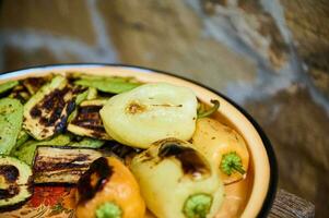 Food background with a metal enamel plate full of freshly cooked bell pepper and zucchinin slices on barbeque grill photo