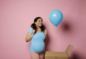 contento embarazada mujer, experimentando alegría y felicidad descubriendo azul globo a género revelar fiesta. esperando bebé chico foto