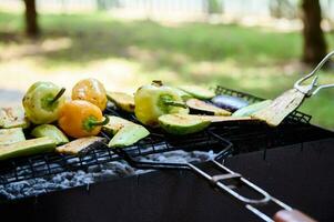 clasificado delicioso A la parrilla vegetales en parilla parrilla con fumar y llamas en verde césped. comida antecedentes. foto