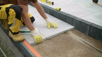 professioneel Kaukasisch arbeider installeren beton bestrating bakstenen patio vloer. industrieel thema. video
