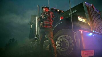 Interstate 80 Truck Stop. Caucasian Truck Driver Staying in Front of His Kenworth Classic Semi Truck During Foggy Night Hours. video