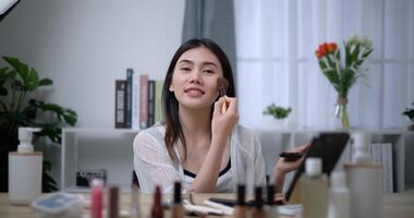 hermosa joven asiático mujer blogger muestra cómo a hacer arriba y utilizar productos cosméticos foto