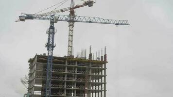 Timelapse, construction of a building in snowy weather. View of a working construction crane on a sky background video