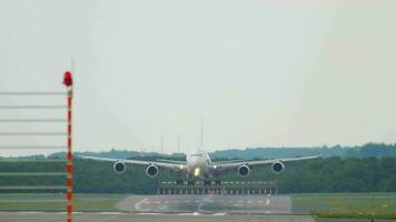 Widebody aircraft landing, touchdown and braking, front view. Cinematic footage of unrecognizable airliner on runway. Airplane silhouette arriving at the airport. Travel and tourism concept video