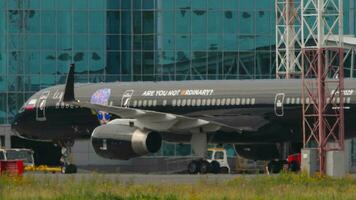 novosibirsk, ruso federación julio 15, 2022 - boeing 757, real academia de bellas artes 73029 de azur aire con lujo Arte alegría librea rodaje a el pista. tractor tira un avión de línea. turismo y viaje concepto video