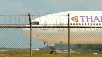 PHUKET, THAILAND NOVEMBER 30, 2019 - Thai Airways Boeing 777 HS TJH named Suphan Buri turn runway and Bangkok Airways ATR 72 turboprop taxiing after landing at background, International Phuket Airport video