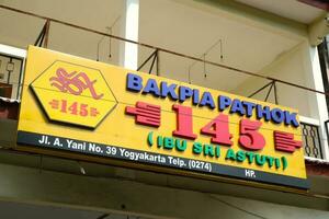 Yogyakarta, Indonesia - March 20, 2023 - Signboard of Bakpia Pathok store around Malioboro tourist area. Bakpia pathok is one of the famous shop that sell javanese food photo