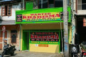 Yogyakarta, Indonesia - March 20 2023 - A traditional eatery called Warteg with bright yellow and green signature color scheme is open for business. Warteg Kharisma Bahari at Bhayangkara street photo