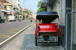 Becak, traditional rickshaw transport is parked on the sidewalk photo