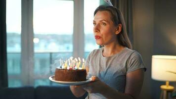 glücklich aufgeregt Frau Herstellung geschätzt Wunsch und weht Kerzen auf Urlaub Kuchen, feiern Geburtstag beim heim, schleppend Bewegung video