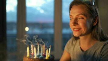 Happy excited woman making cherished wish and blowing candles on holiday cake, celebrating birthday at home, slow motion video