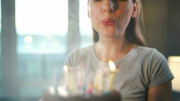 Happy excited woman making cherished wish and blowing candles on holiday cake, celebrating birthday at home, slow motion video