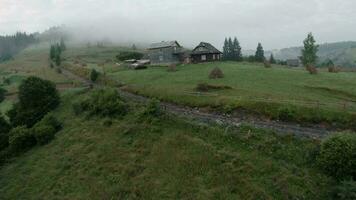 Maneuverable flight in the morning fog over a mountain village on FPV drone video