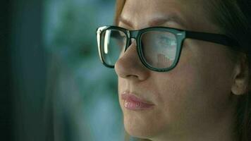 Woman in glasses looking on the monitor and and working with charts and analytics. The monitor screen is reflected in the glasses video