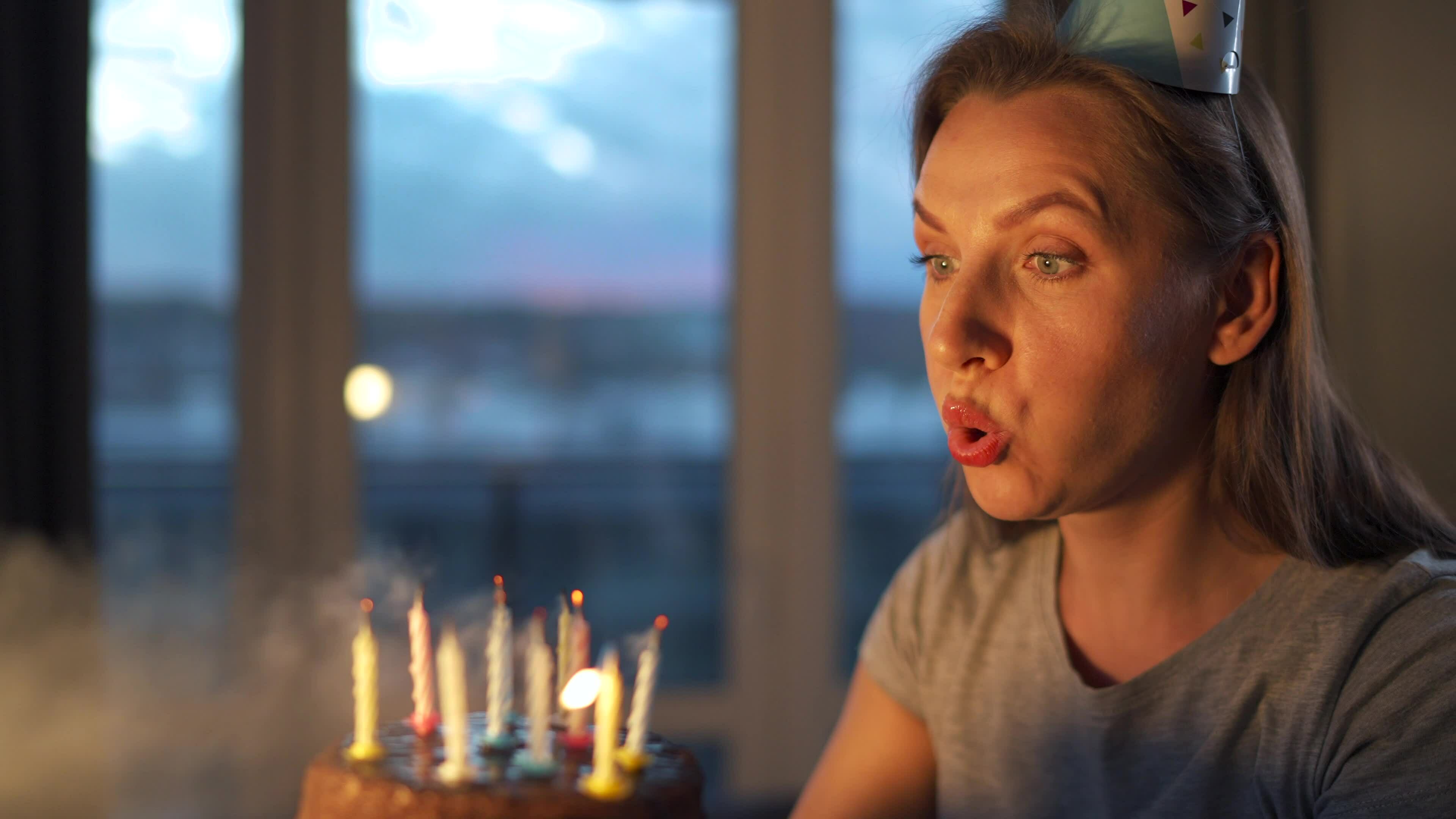 Happy excited woman making cherished wish and blowing candles on