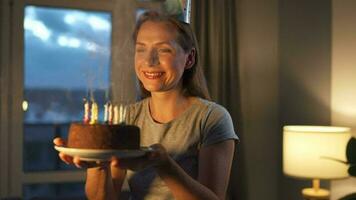 content excité femme fabrication chéri souhait et soufflant bougies sur vacances gâteau, célébrer anniversaire à maison, lent mouvement video