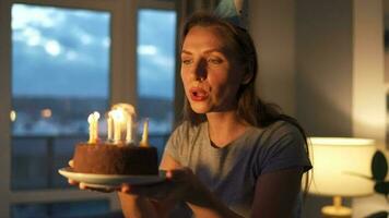gelukkig opgewonden vrouw maken gekoesterd wens en blazen kaarsen Aan vakantie taart, vieren verjaardag Bij huis, langzaam beweging video