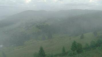 Maneuverable flight in the morning fog over a mountain village on FPV drone video