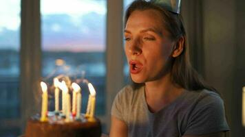 Happy excited woman making cherished wish and blowing candles on holiday cake, celebrating birthday at home, slow motion video