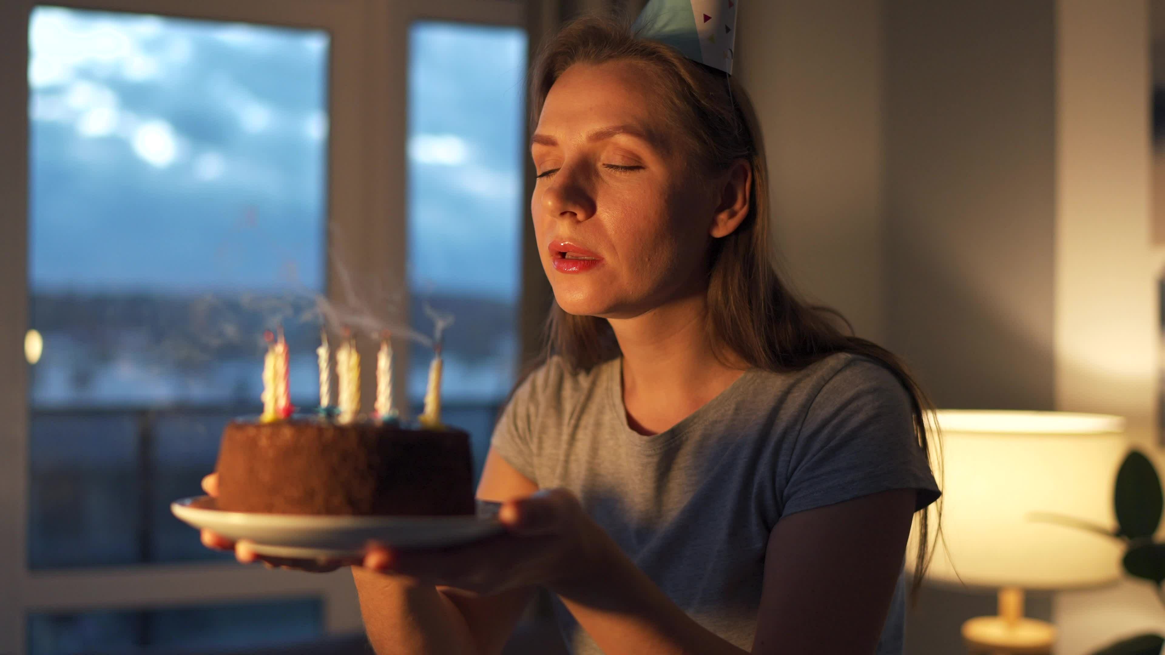 Happy excited woman making cherished wish and blowing candles on