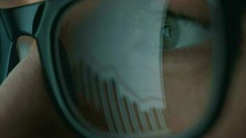Woman in glasses looking on the monitor and and working with charts and analytics. The monitor screen is reflected in the glasses video