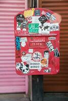 Maehongson, Thailand - December 11, 2016 Dirty red old mailbox stand between pink and red steel wall photo