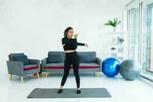 asiático joven sano mujer en material deportivo practicando yoga a hogar, deporte niña ejercicio en vivo habitación a hogar foto