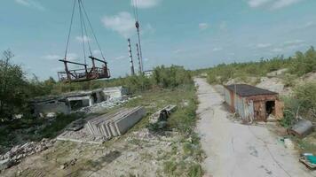 fpv zumbido moscas suavemente entre abandonado industrial edificios y alrededor un excavador video