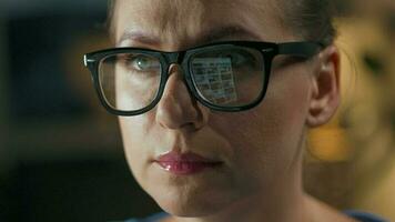 Woman in glasses looking on the monitor and surfing Internet at night. The monitor screen is reflected in the glasses. Work at night video