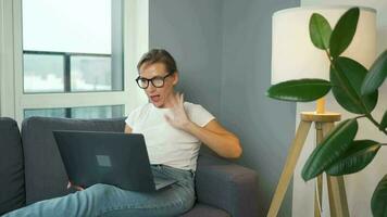 Casual dressed woman with glasses sitting on the sofa and communicates via video link with family or close friends