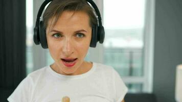 mujer en auriculares limpia el casa y tener divertido canto con un Escoba me gusta un estrella a un concierto video