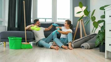 Tired couple sits on the floor in a room and high five each other after they finish cleaning the house video