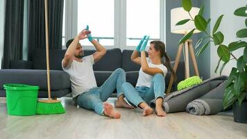 Tired couple sits on the floor in a room and high five each other after they finish cleaning the house video