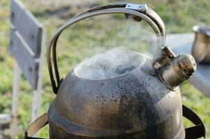 Kettle with water on the stove outside. Boiling water in difficult times. photo