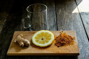 Turmeric and lemon on a wooden cutting board with copy space. photo