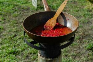 Cooking in the yard during difficult times. A frying pan in which dressing for borscht is prepared on the stove in the yard.. photo