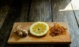 Turmeric and lemon on a wooden cutting board with copy space. photo