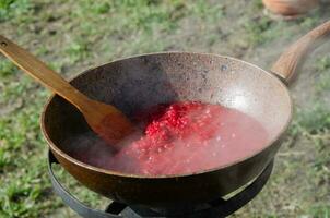 Cooking in the yard during difficult times. A frying pan in which dressing for borscht is prepared on the stove in the yard.. photo