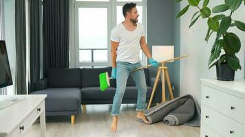 Man cleaning the house and having fun dancing with a broom. Slow motion video