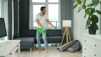 Man in headphones cleaning the house and fooling around with a broom video