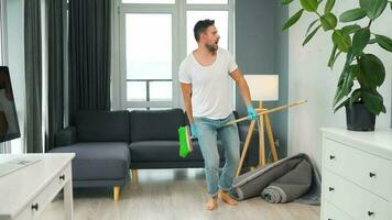 Man cleaning the house and having fun dancing with a broom. Slow motion video