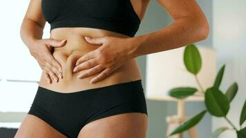 mujer apresamiento el piel en su estómago y lados comprobación para celulitis y exceso subcutáneo grasa video