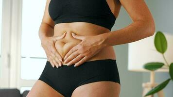 Woman compressing the skin on her stomach and sides checking for cellulite and excess subcutaneous fat video