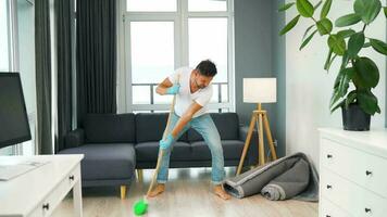 Man cleaning the house and having fun dancing with a broom. Slow motion video