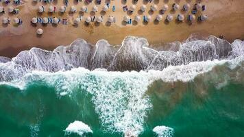 aereo Visualizza di il mare, sabbioso spiaggia, sole ombrelli e lettini, irriconoscibile le persone. bellissimo vacanza e turismo video