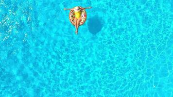 Antenne Aussicht von ein Frau im Gelb Badeanzug Lügen auf ein Krapfen im das Schwimmbad video